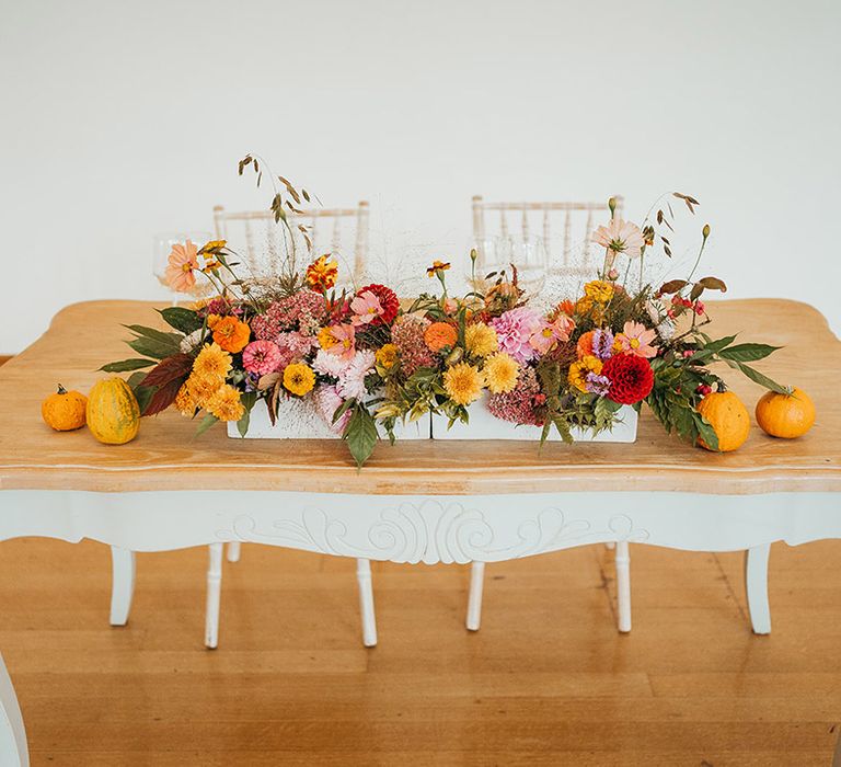 Bright colourful seasonal wedding flowers decorating the wedding table with mini pumpkins 