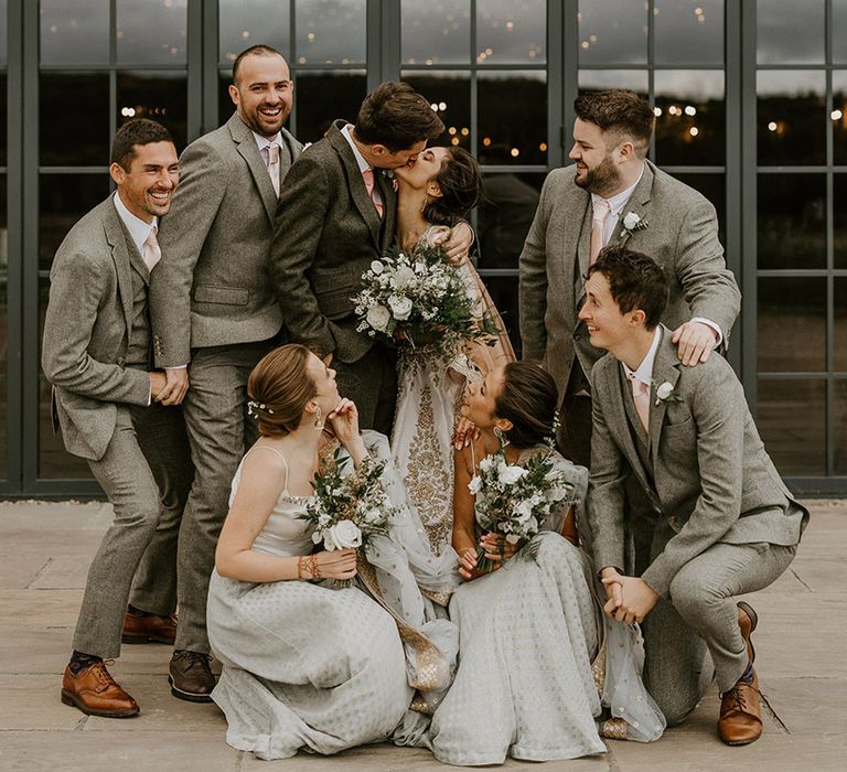 The wedding party pose together in neutral grey wedding outfits with sparkly details 