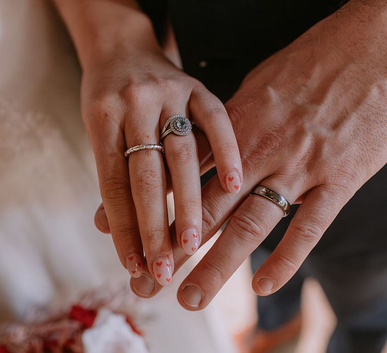 The bride places her hand over the grooms to show off her heart patterned nail art on these themed engagement nails