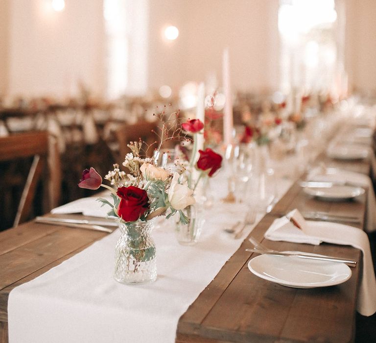 White and red roses in bud vases for Christmas wedding table decorations 