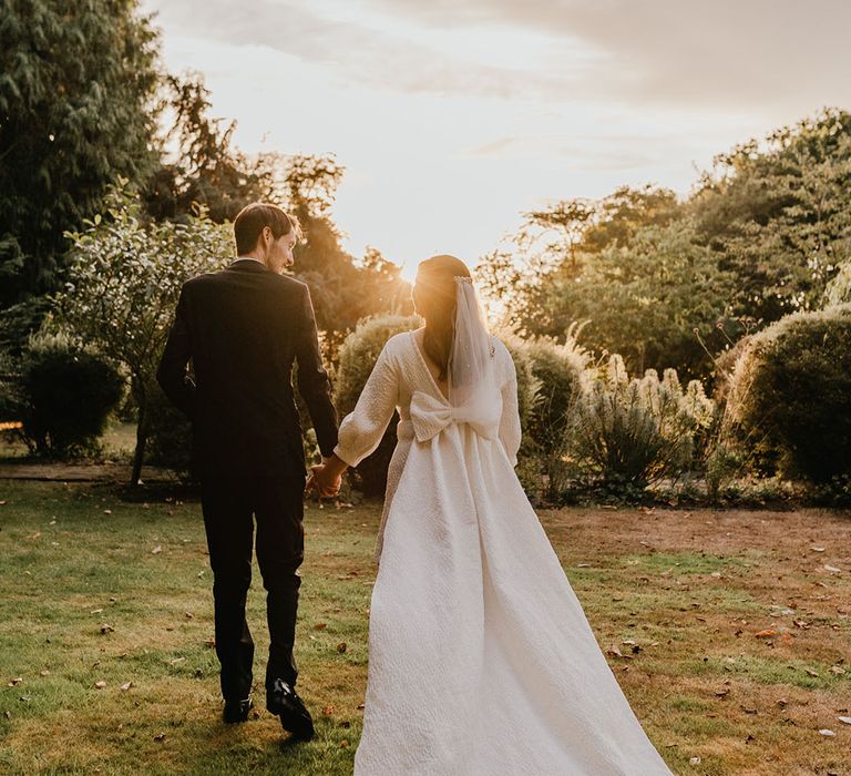 Bride wearing a short textured wedding dress with an attachable train with back bow detail 