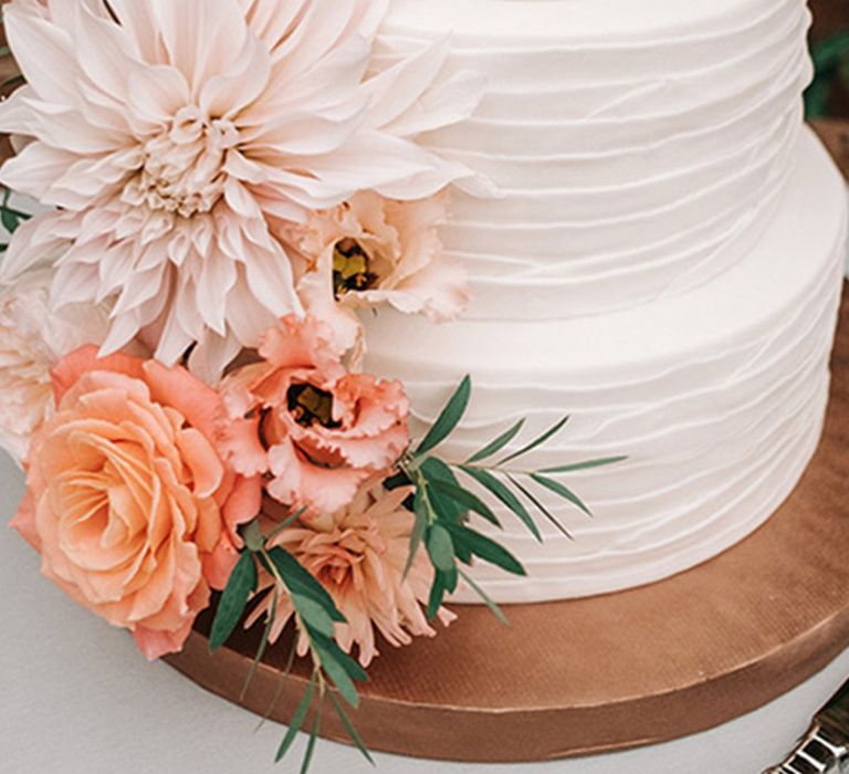 Three tier white iced wedding cake with dahlia peach wedding flowers 