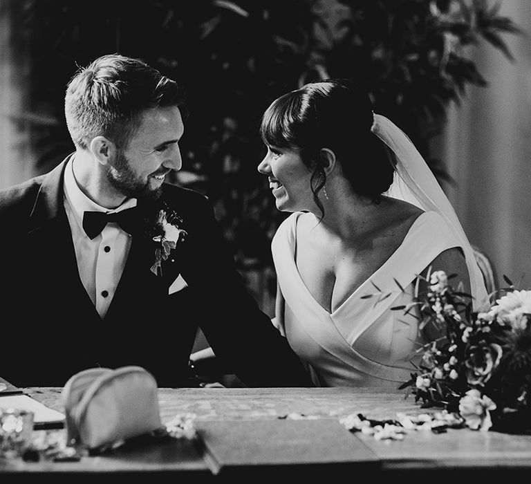 Bride and groom sit together to sign their wedding registry 