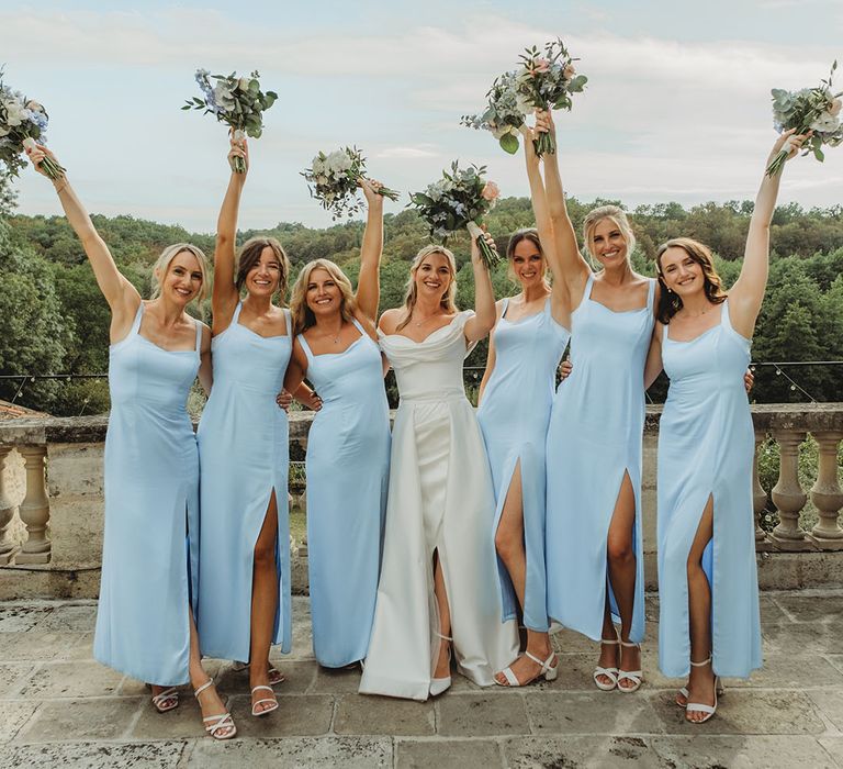 Bridal party in powder blue bridesmaid dresses with white flower bouquets at destination wedding in Chateau Lagorce 