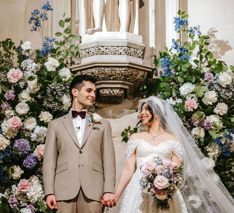 Pastel pink, purple, blue and white wedding flowers with the bride and groom at their ceremony 