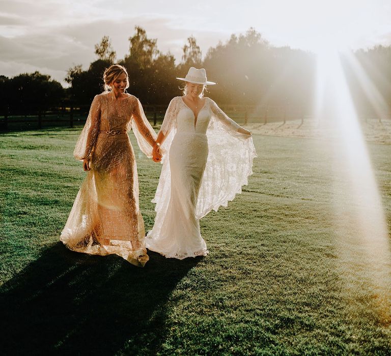 Sunset golden hour wedding photo with two brides in sparkly wedding reception dresses and outfits 