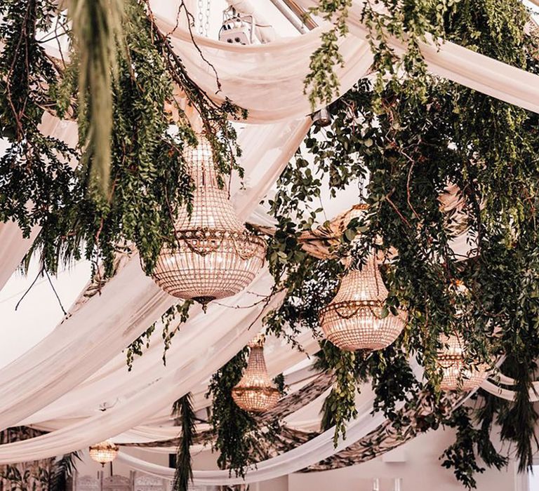 Marquee wedding breakfast decorated with lots of foliage and greenery 