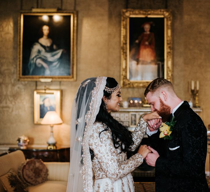 Groom in tuxedo kissing his brides hand at Syon Park wedding