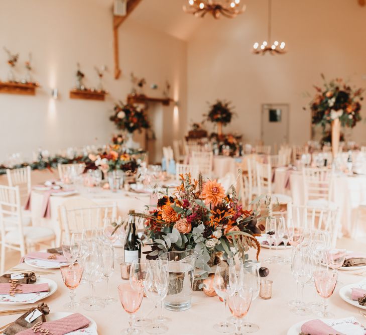 Wedding table decor at Millbridge Court with floral centrepiece, coloured wine glasses and napkins. 