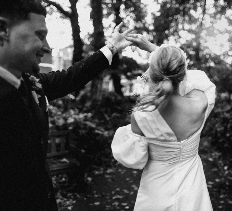 Groom spins the bride around to show off her puff sleeve ruched wedding dress