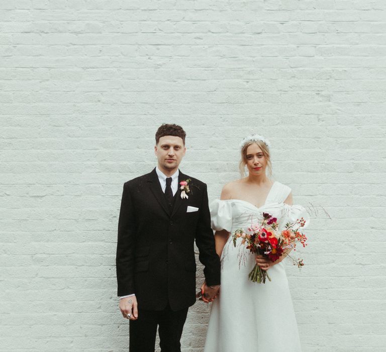 Married couple hold hands with groom in traditional suit and bride in dramatic puff sleeve dress