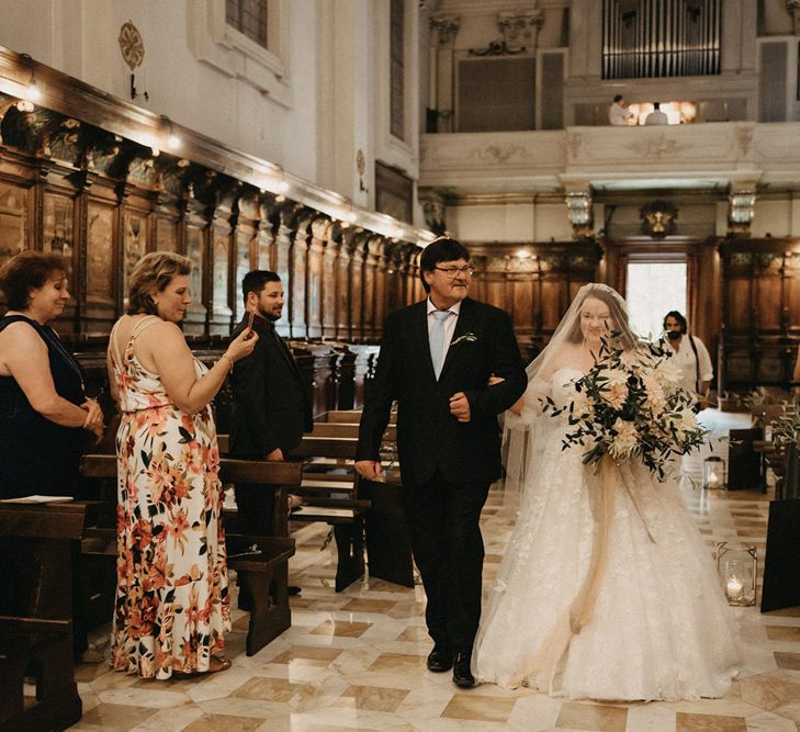 Saskia walks down the aisle with a huge olive bouquet