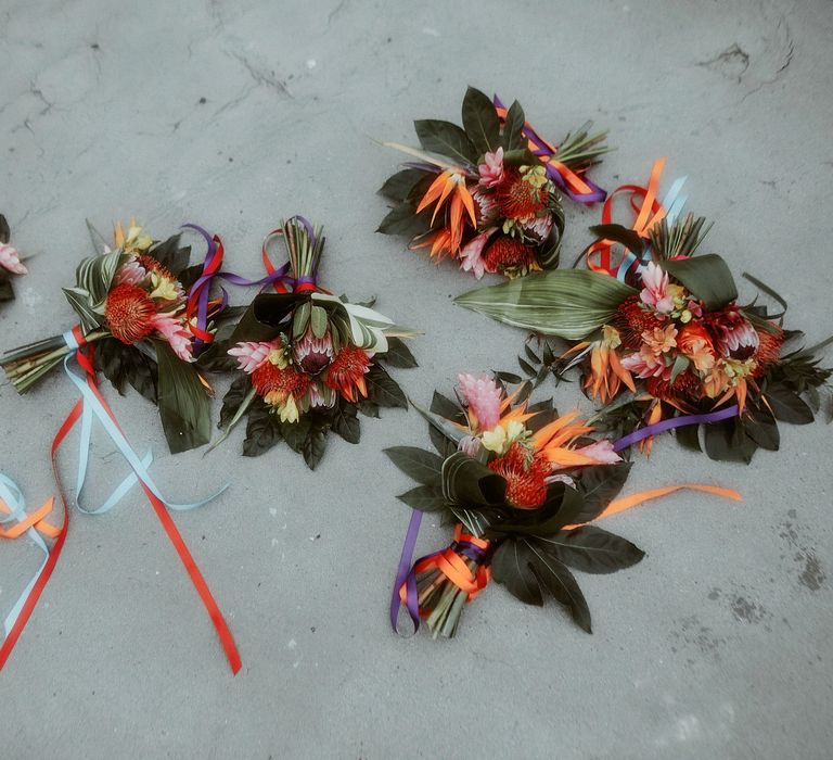 Colourful tropical wedding bouquets tied with ribbon including proteas 