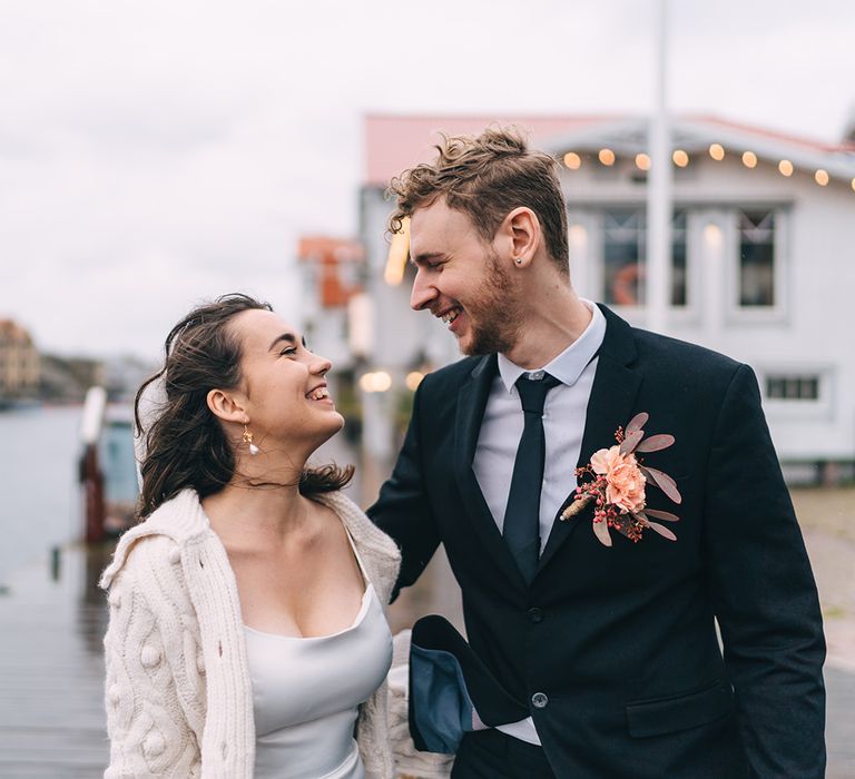 The bride and groom smiling at each other next to the sea in Smogen, Sweden