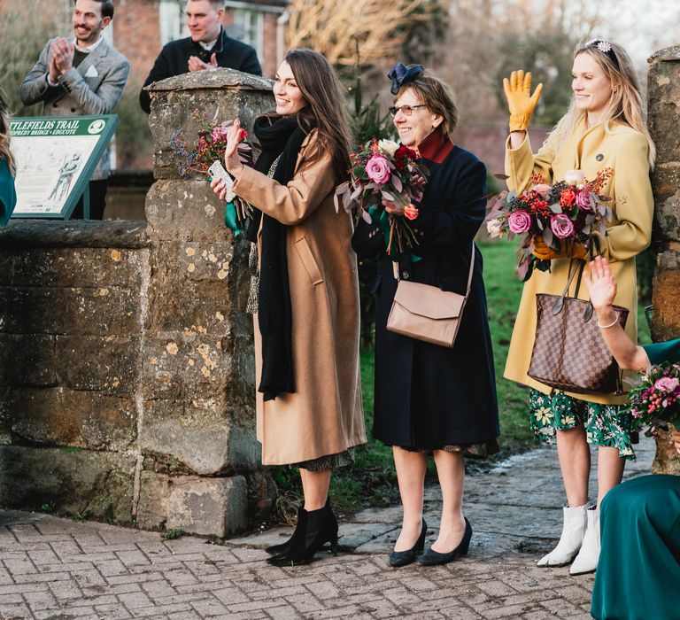 Wedding guests gather socially distanced outdoors to see bride & groom