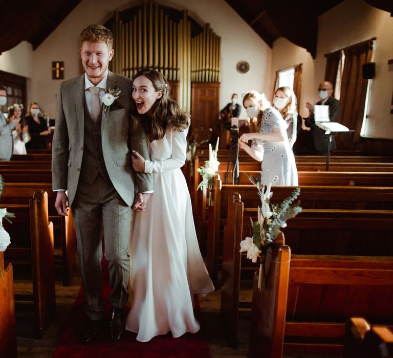 The bride and groom walk down the aisle, just married