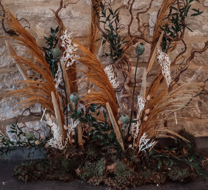 Orange and green wedding floral arrangement with dried grasses, moss, foliage and poppy seeds