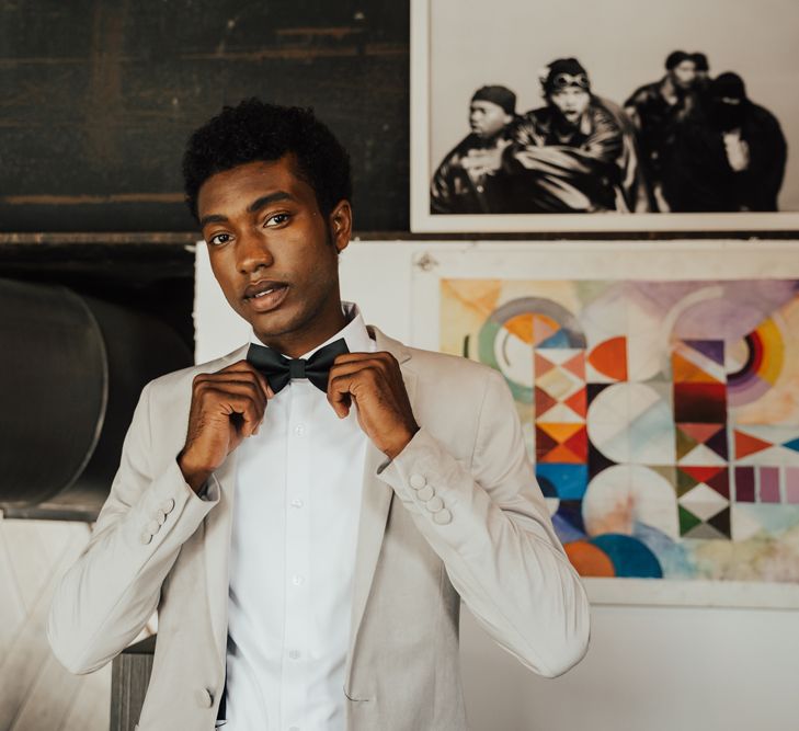 Stylish groom in a white shirt, black bow tie and grey blazer 