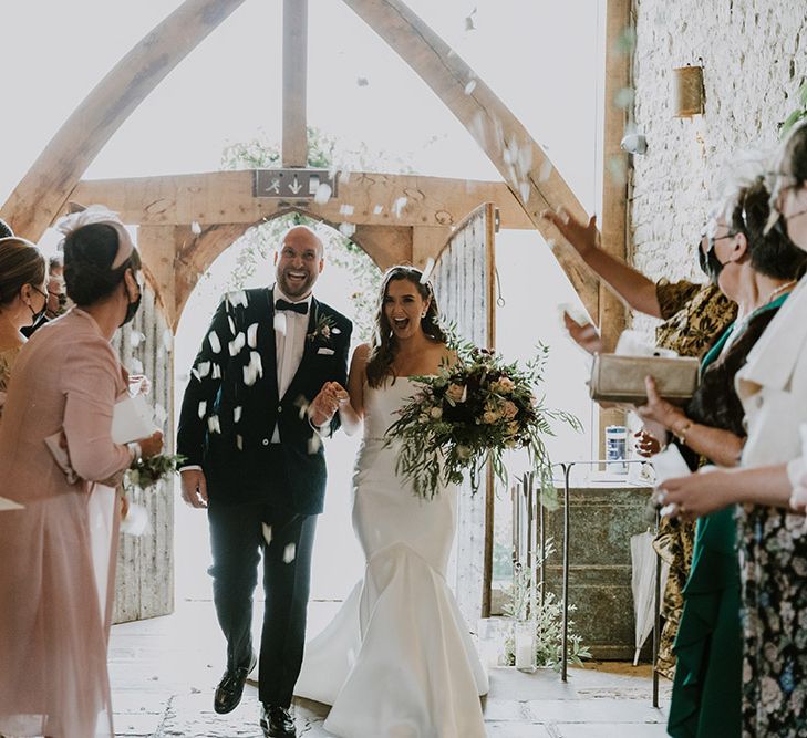 Bride and groom confetti moment at Cripps Barn with groom in velvet tuxedo and bride in a fishtail wedding dress