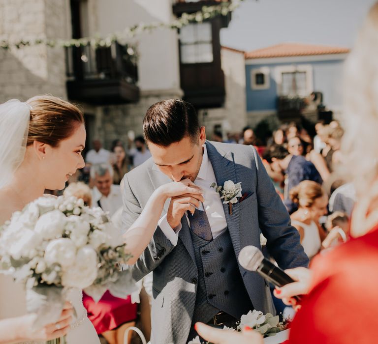 Groom kissing the bride's hand as they get married