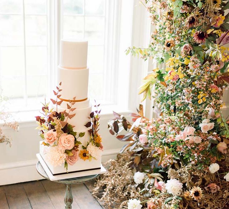 Six tier iced wedding cake with square and round layers and autumn flower decor 