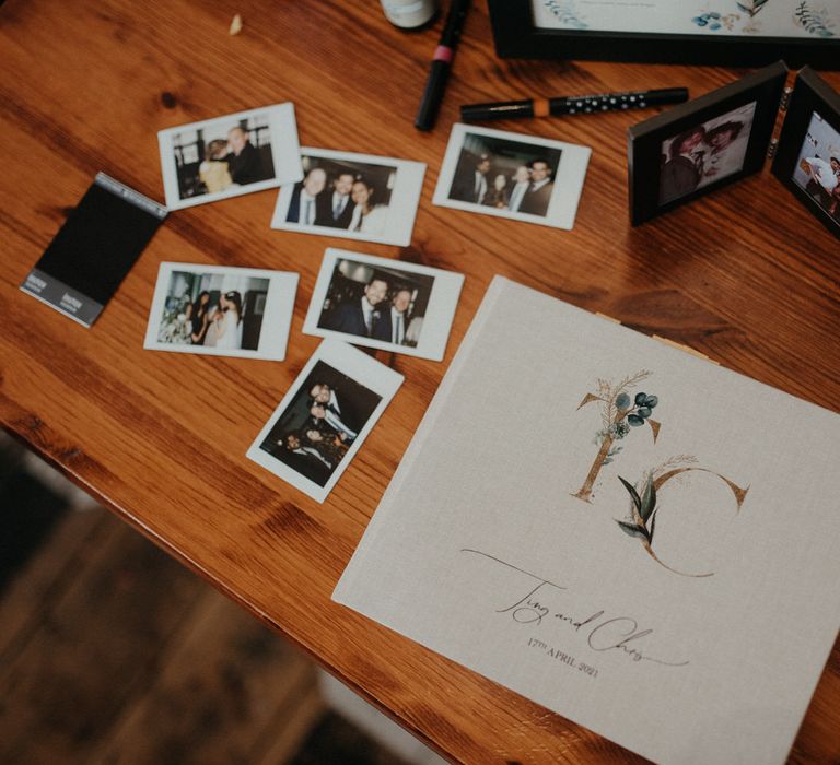 Linen guestbook with initials, on a table with polaroid photos