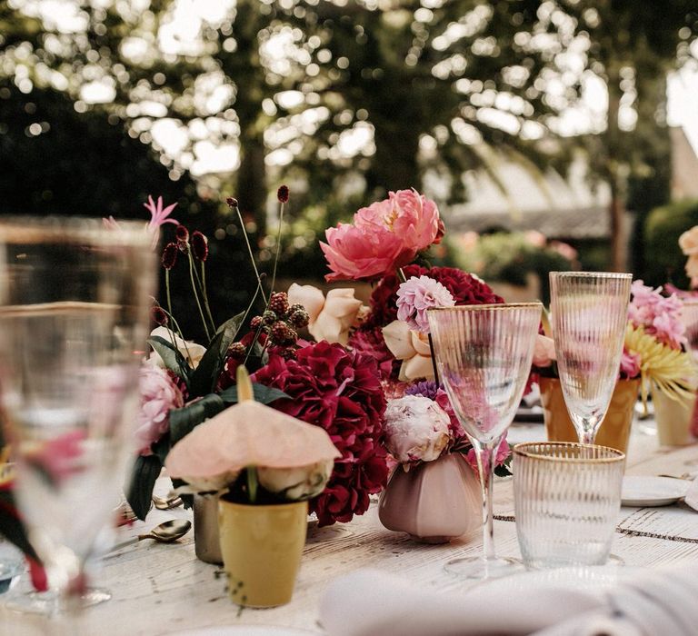 Romantic pink tablescape with pink floral centrepieces, gold rimmed glassware and white tableware