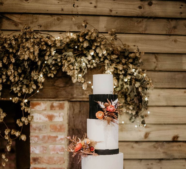 Four tier black and white wedding cake with rose gold floral details by Amalina Bakes