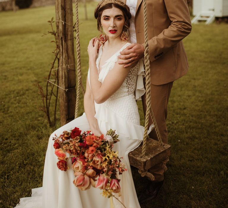 Bride clutching large bouquet with groom at boho wedding