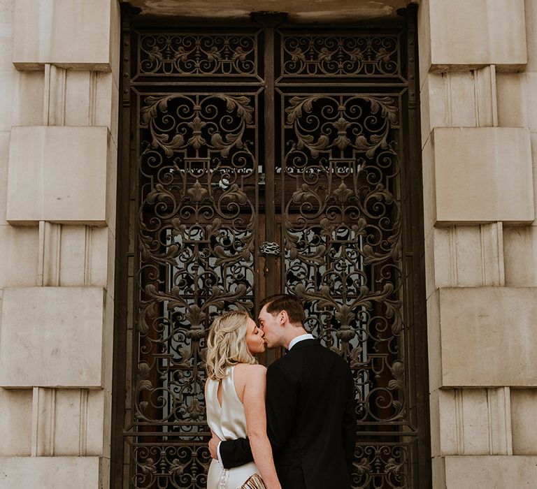 Bride and groom kissing outside Leeds Civic Hall with bride in a champagne colour wedding dress and groom a black suit 