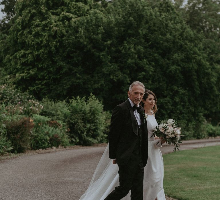 Bride walks down the aisle with her father on the day of her wedding