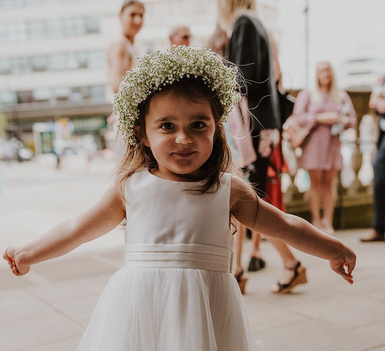 Beautiful flower girl in a white tulle skirt dress with gypsophila flower crown 