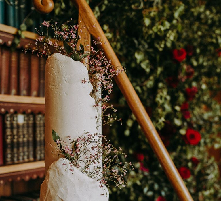 Sculptured wedding cake by B Bakes London with wild flower decor resting on a wooden step ladder in the Library at Dulwich College