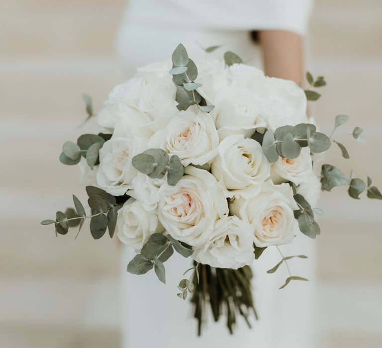 Bride holds bright white floral bouquet complete with green foliage | Hannah MacGregor Photo & Film