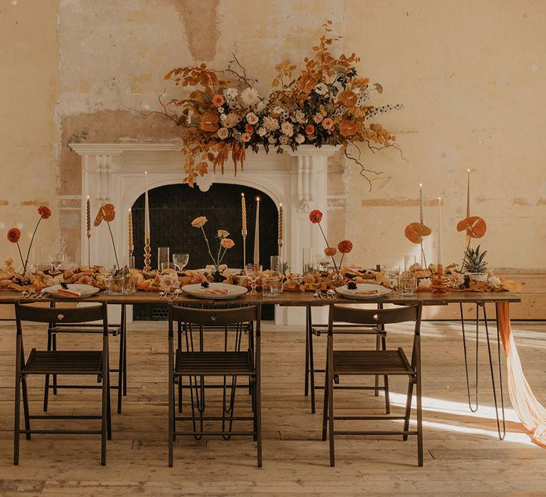 Fireplace at Clerkenwell House decorated with orange autumnal flowers with an intimate tablescape laid out in front 