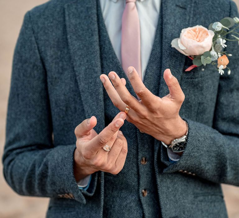 Groom in a three-piece blue wool suit with pale pink tie and peach David Austen Rose buttonhole flower 