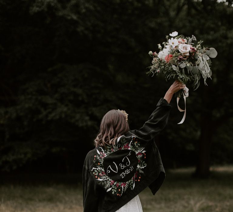 Bride wears personalised black denim jacket with floral illustrations 