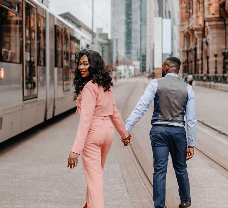 Bride & groom walk hand in hand through Manchester