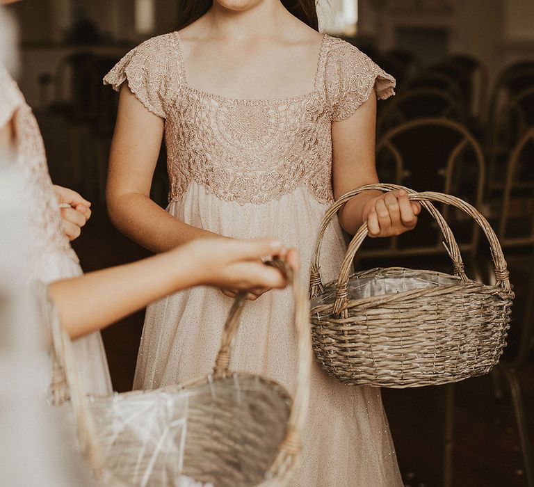 Flower girl wears neutral bridesmaids dresses and carries wicker basket