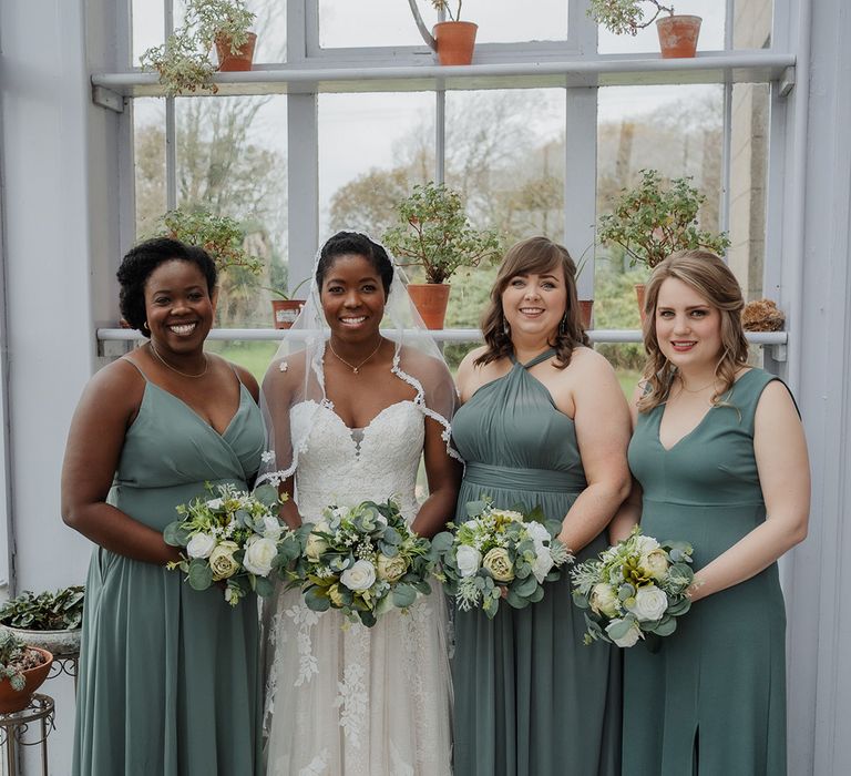 Bride stands in lace edge wedding veil & sweetheart wedding dress with her bridal party 