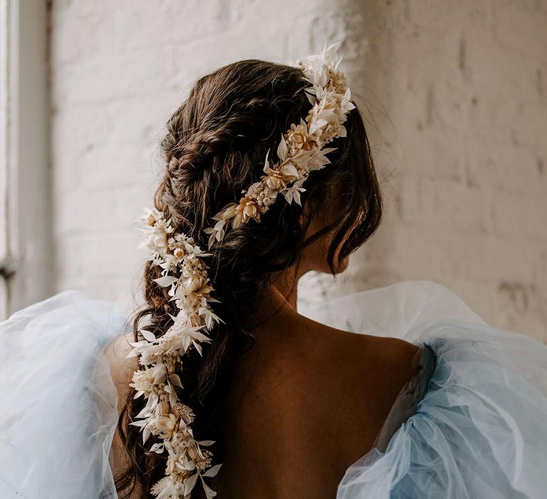 Bride in a blue tulle wedding dress with a dried flower halo trailing down their braided ponytail 