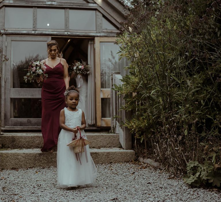 Bridesmaid stands with flower girl on wedding day