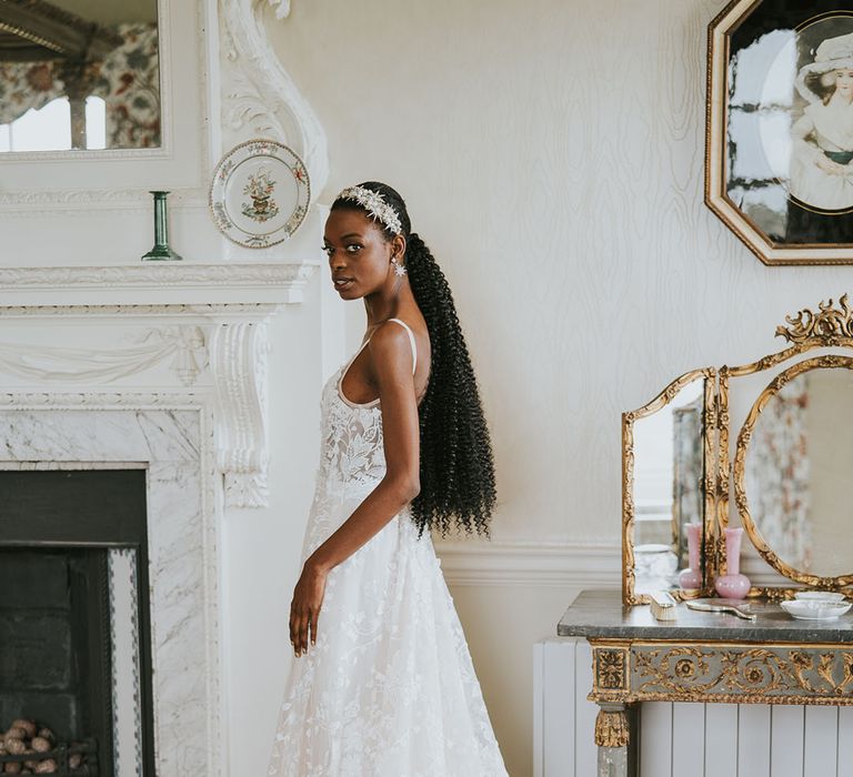 Black bride with long afro hair tied in a ponytail in a lace Made With Love wedding dress 