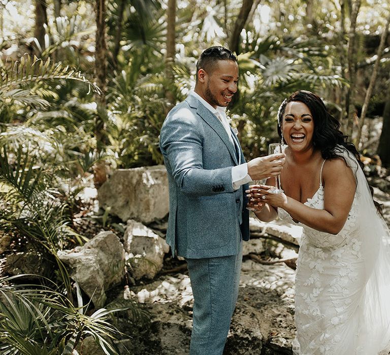 Bride in lace floral wedding gown laughs with groom at outdoor destination wedding 