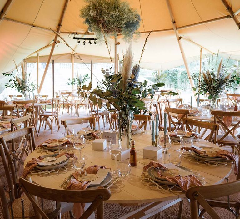 Tablescape with blue twisted candles, dried flower bouquets with pastel colourings and pink napkins with gypsophila cloud