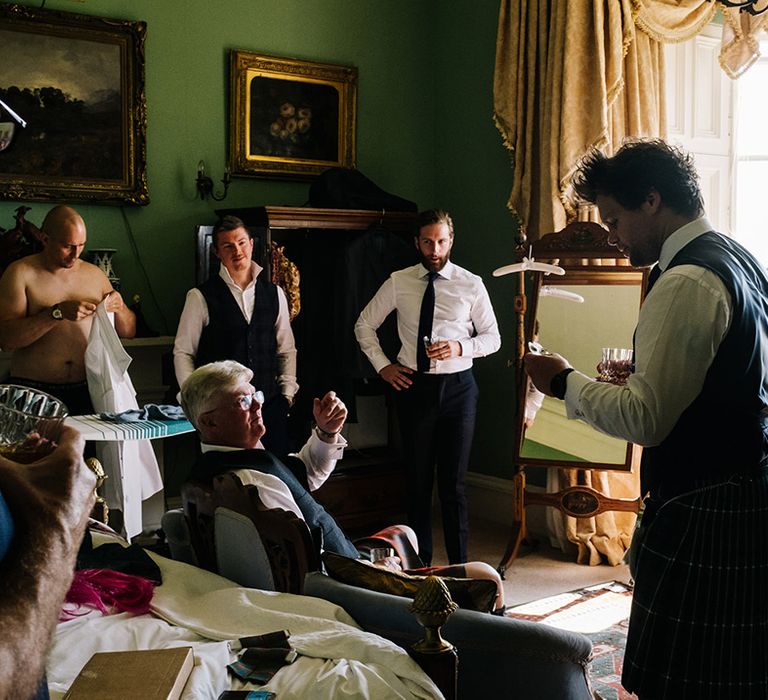 Groomsmen get ready for the wedding together as they put on their outfits