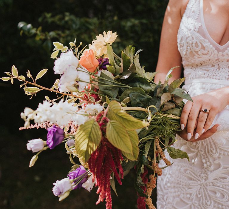 Bride in v-neck lace wedding dress from Made With Love Bridal with baby pink nails and colourful wedding bouquet