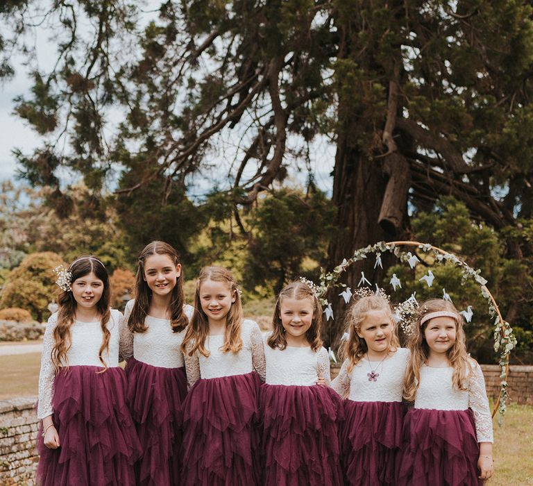 Six flower girls in matching lace and purple flower girl dresses with tulle and gypsophila hair accessory 