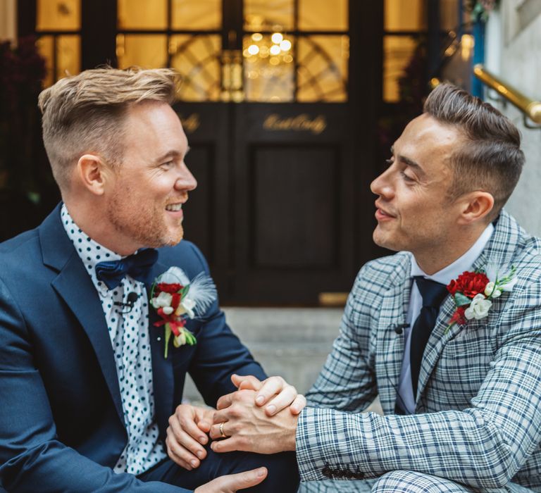 Grooms laugh with one another on their wedding day