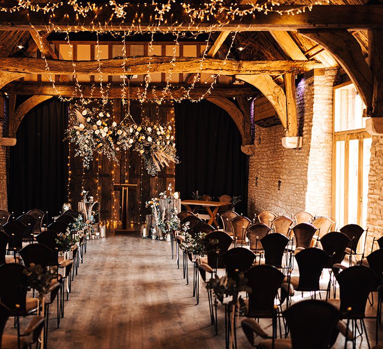 Tythe Barn wedding venue with fairy lights, candle lanterns with exposed beams and orange and white flower displays